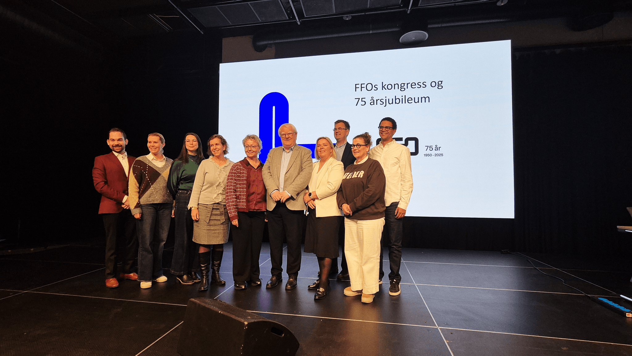 Flere personer står oppe på en scene. De smiler alle til kamera. Bak dem står teksten: FFOs kongress og 75 årsjubileumsmarkering.