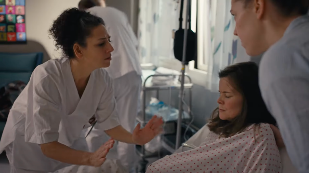 På en fødestue ligger en kvinne og en sykepleier forsøker å roe henne ned.