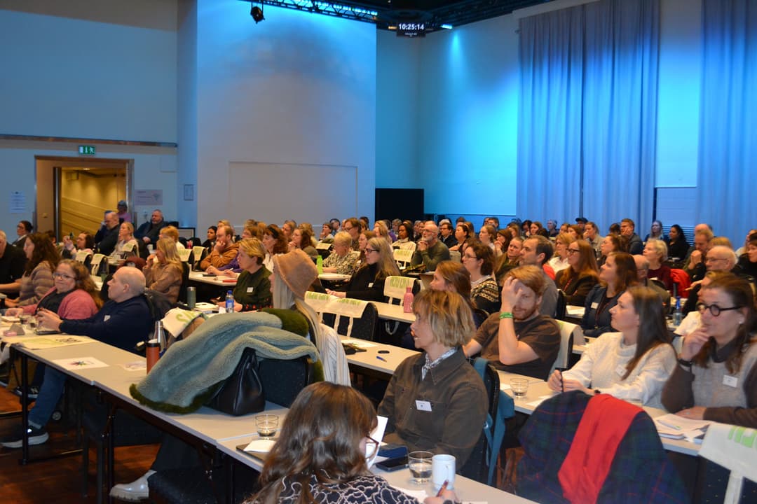 Mange personer sitter å følger med på et foredrag.