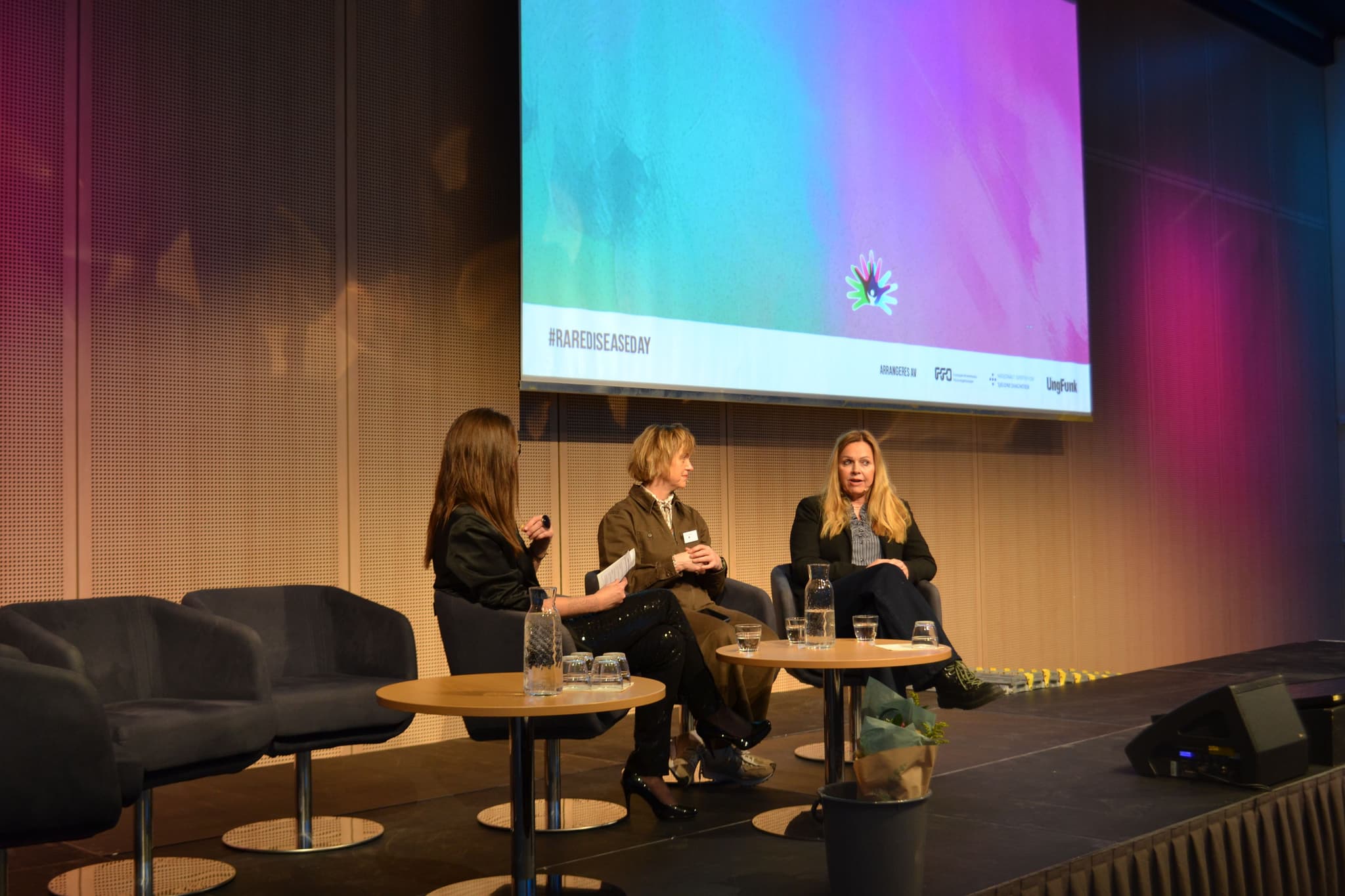 Flere personer sitter på en scene og har en samtale.