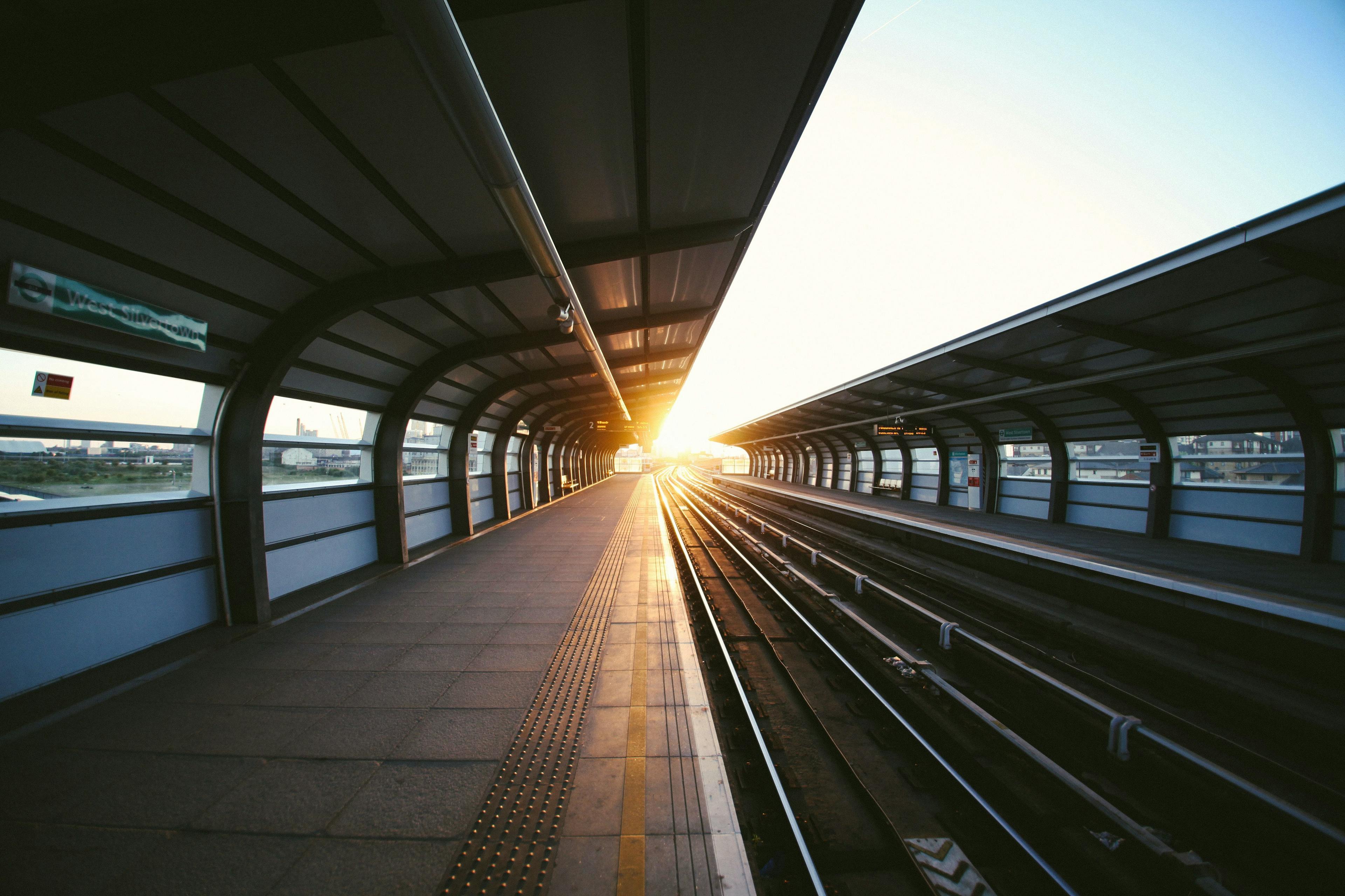 En tom togperrong hvor solen skinner sterkt mot togsporene.