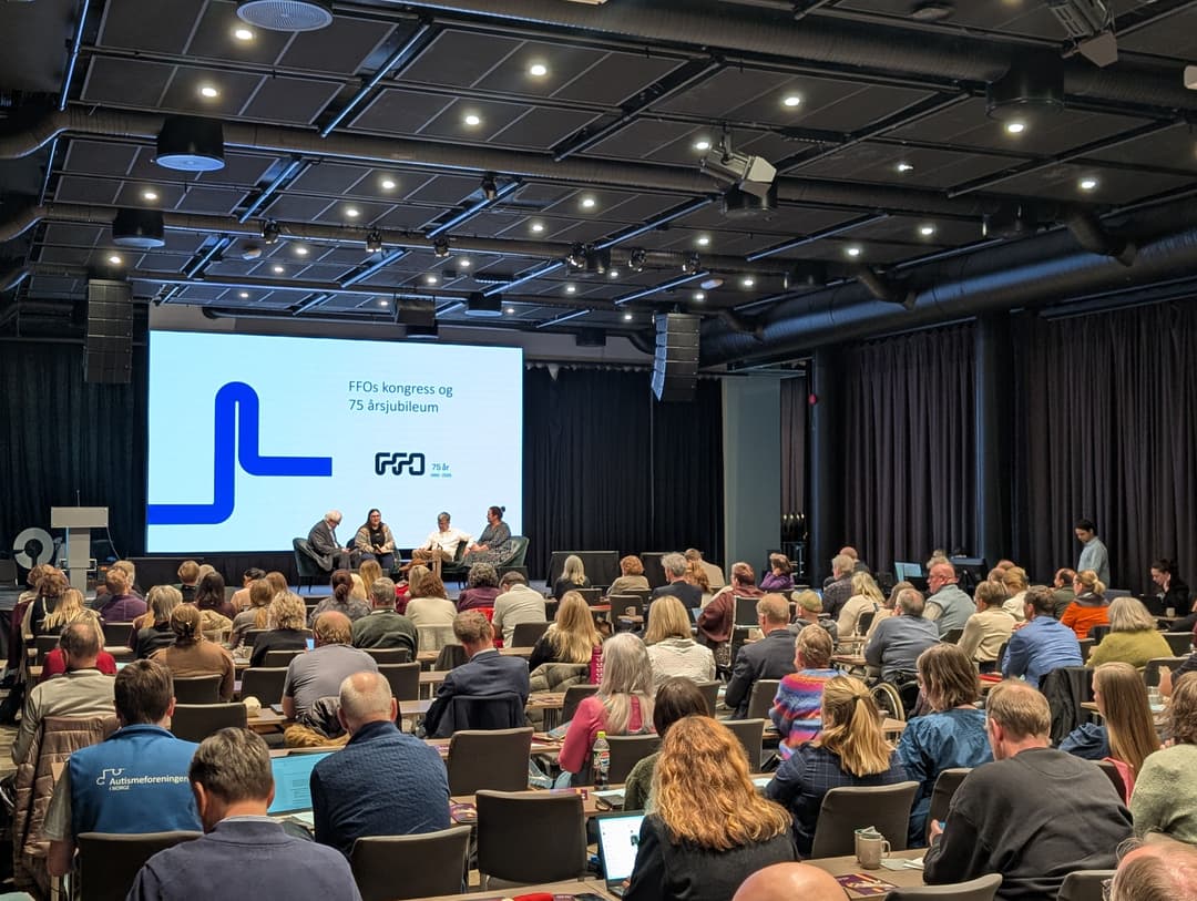 Mange personer sitter samlet i en stor sal. Oppe på scenen sitter fire personer å fører en samtale. Bak dem er det en stor skjerm hvor det står FFOs kongress og 75 årsjubileum. Under er logoen til FFO hvor det står 75 år 1950-2025.