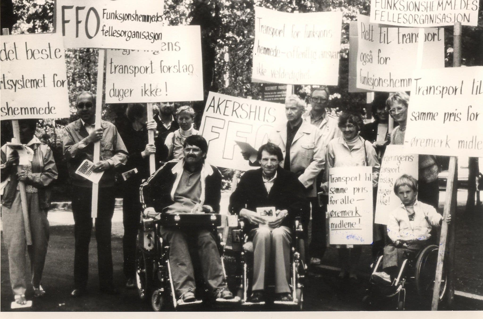 Bilde viser flere personer. Noen sitter i rullestol. Flere holder skilt med ulik tekst på. Dette er i forbindelse med en demonstrasjon FFO hadde på 80-tallet.