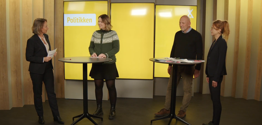 Tre kvinner og en mann står i et studio, de står ved to runde bord. Bak de står det skjermer med gul bakgrunn. På den ene skjermen står det: Politikken.